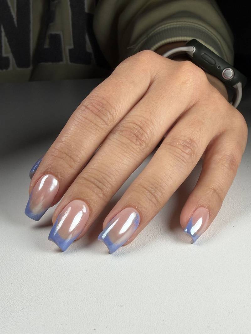 Long nails with a periwinkle-blue french tip and a glossy glass-like finish — by Alice Garrido