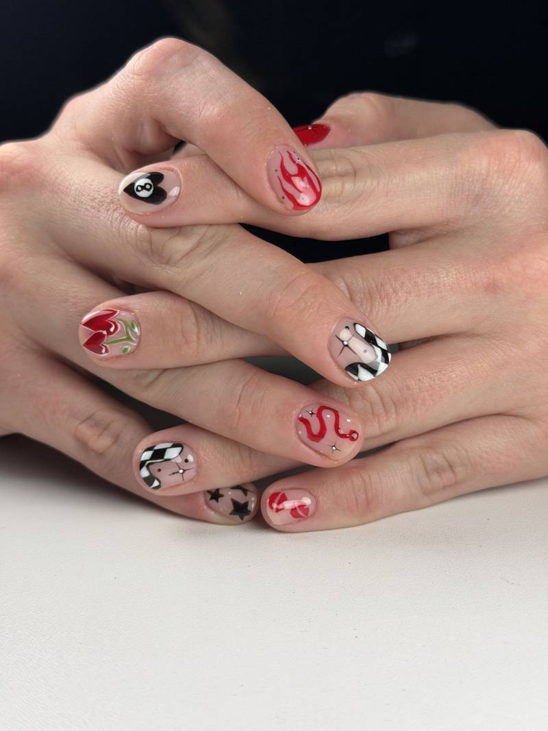 Short nails with bold hand-painted art: an 8-ball heart, red flames, checkerboard, stars and hearts — by Alice Garrido