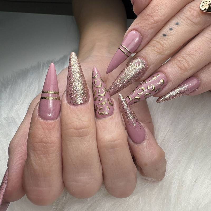 Long mauve stiletto nails with gold glitter, gold stripes and leopard-print accents — by Alice Garrido